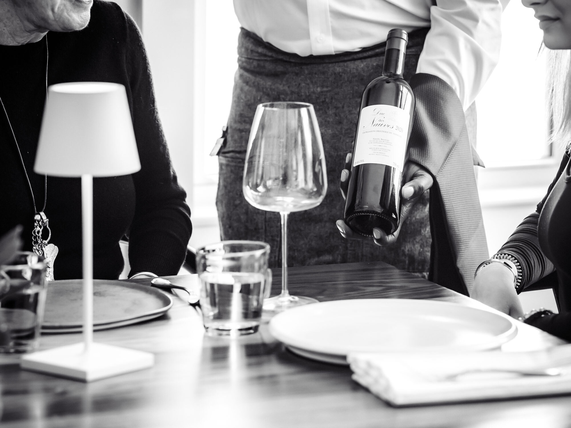 Waiter showing guests bottle of wine